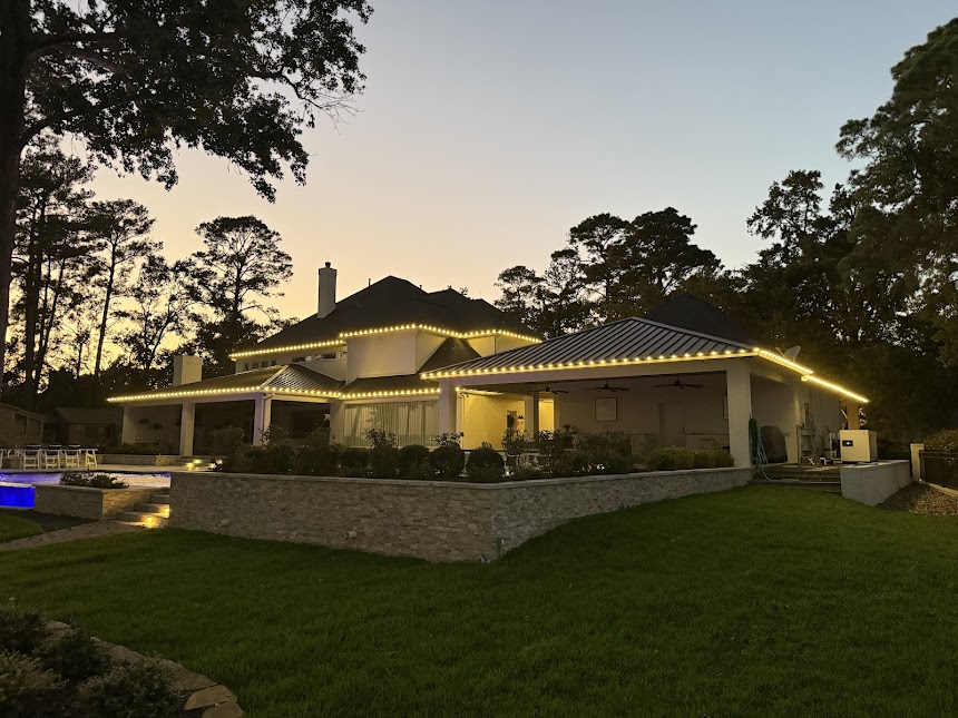Large estate home rooflines outlined in warm white lights at dusk