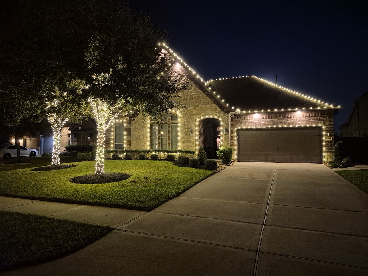 Home with warm white rooflines, windows, and wrapped front-yard trees